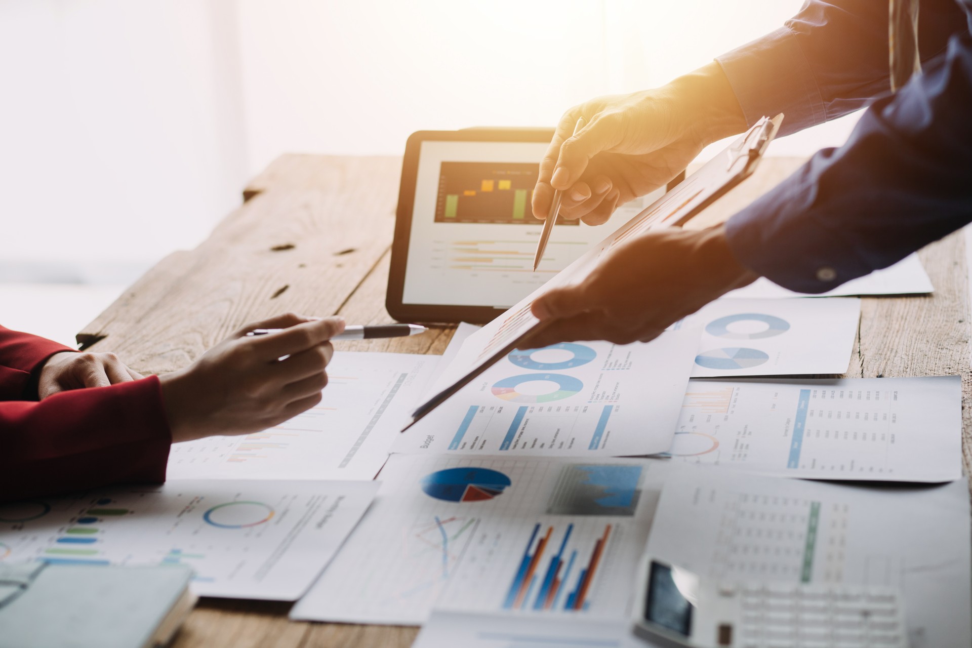 Financial analysts analyze business financial reports on a digital tablet planning investment project during a discussion at a meeting of corporate showing the results of their successful teamwork.